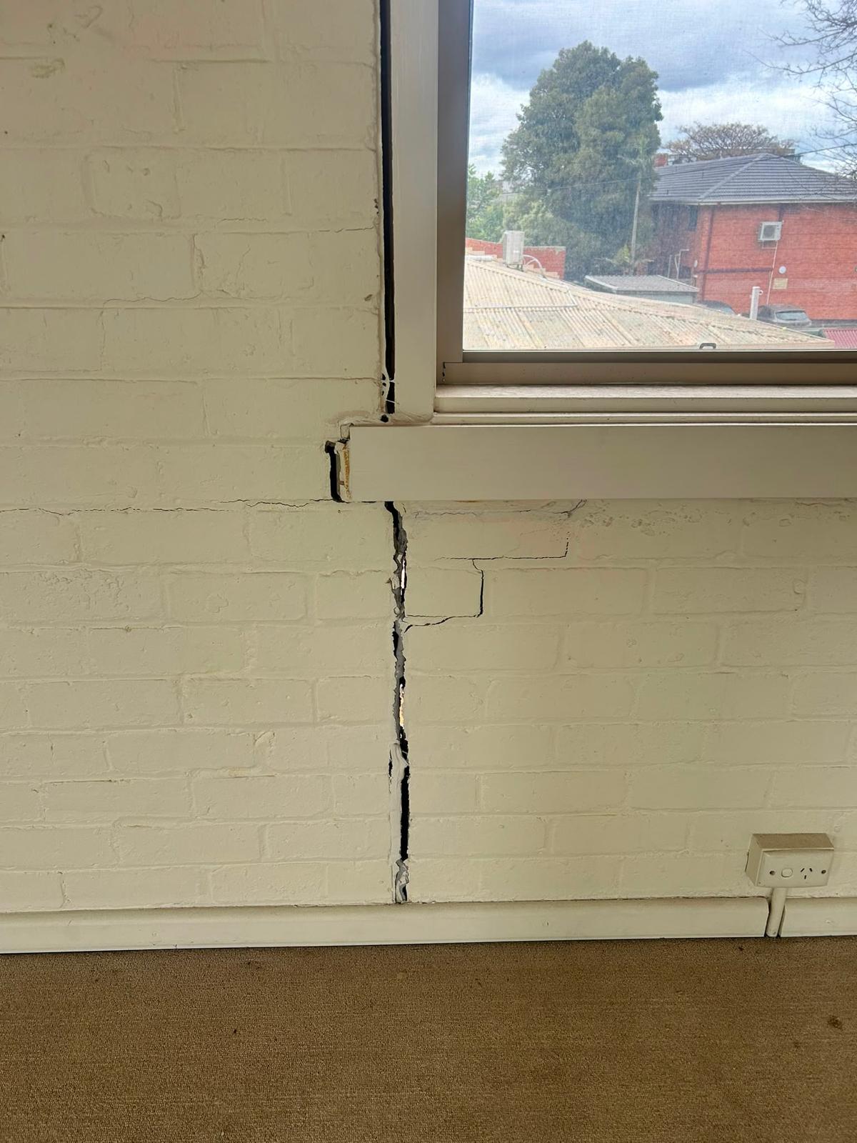 Cracked masonry wall below a window under forensic inspection